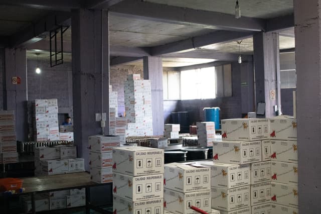 Cajas selladas con el sello Calidad Insuperable, apiladas y listas para despacho