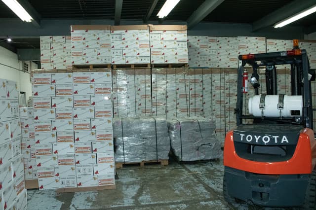 Montacargas moviendo tarimas de cajas en la bodega de despacho